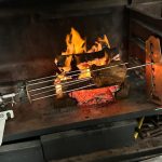Metal skewer over an open flame in a forge setting